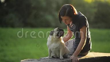 年轻漂亮的女人在<strong>公园里</strong>给她的狗吹吻，可爱的警察亲吻一个女孩，狗和主人<strong>坐在公园里</strong>